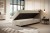 Beiges Boxspringbett mit aufgeklapptem Bettkasten im hellen Zimmer