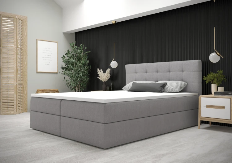 Modernes graues Boxspringbett in einem stilvoll eingerichteten Schlafzimmer.