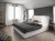 Modernes Schlafzimmer mit grauem Polsterbett und geometrischer Tapete.
