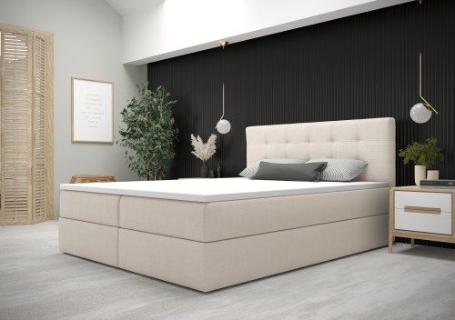 Helles Boxspringbett in Beige vor einer dekorativen schwarzen Wandpaneele.